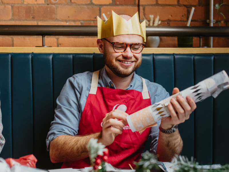 Smiling man in Christmas crown holding a bonbon